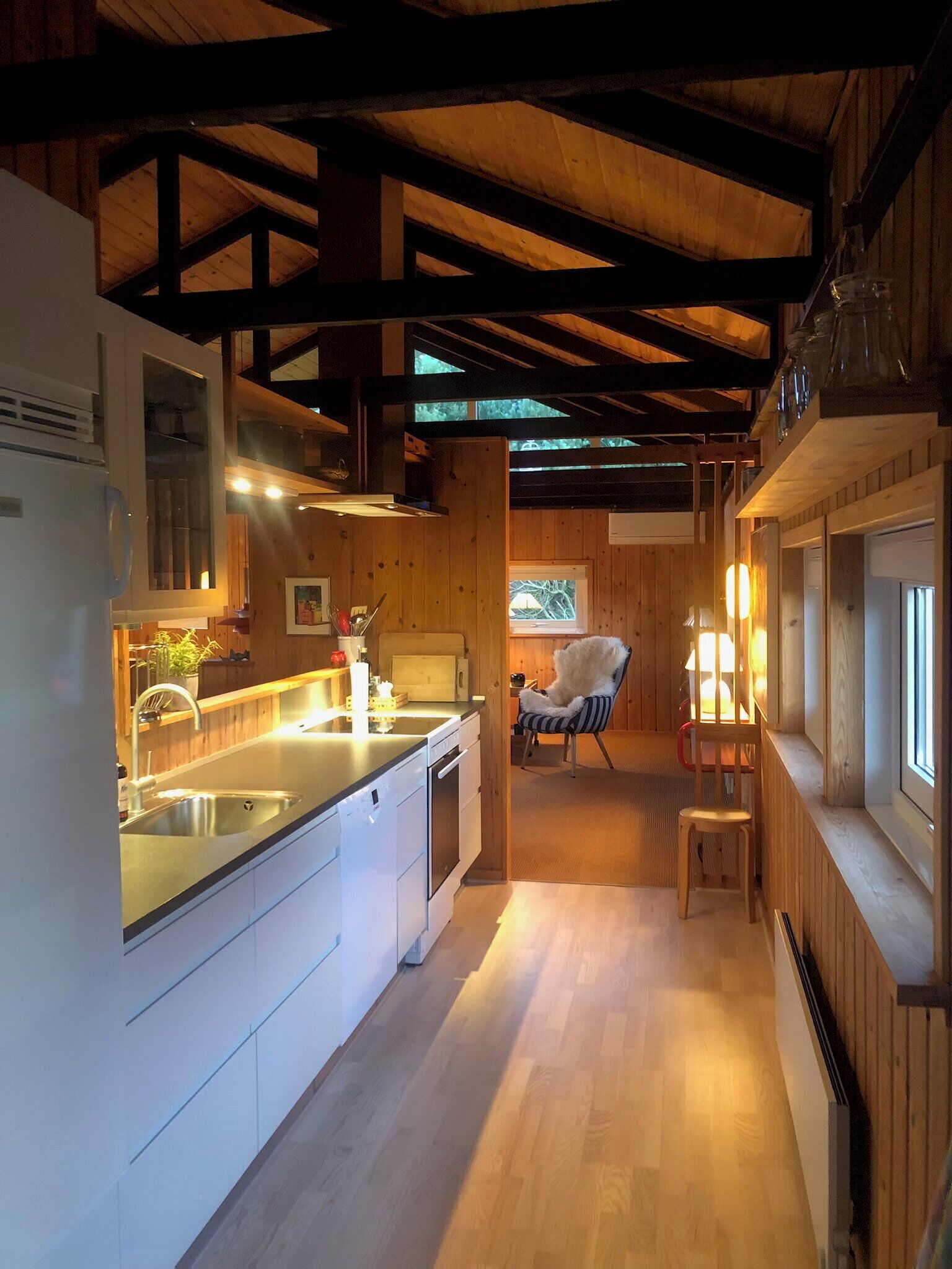 Una cocina moderna con vigas de madera, un lavamanos y un área de comedor con una silla.