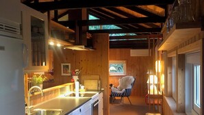 A modern kitchen with wooden beams, a sink, and a dining area with a chair.