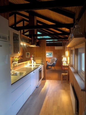 A modern kitchen with wooden beams, a sink, and a dining area with a chair.