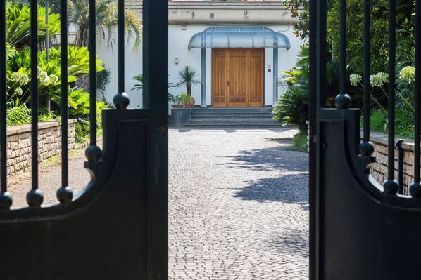 A cobblestone pathway leading to a building with a wooden door and a blue awning.