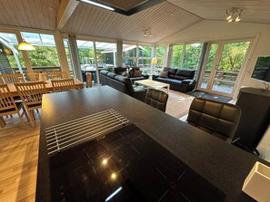 Une cuisine moderne dotée d’un îlot central, d’un coin repas avec des chaises en bois, d’un canapé et d’un téléviseur.