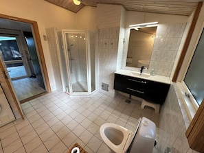 A modern bathroom with a shower, toilet, and sink.