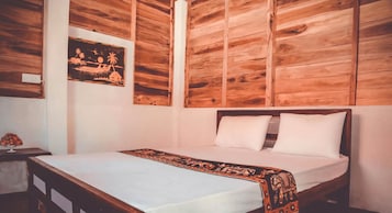 Quarto com cabeceira de madeira, cama com roupa de cama branca e manta decorativa.