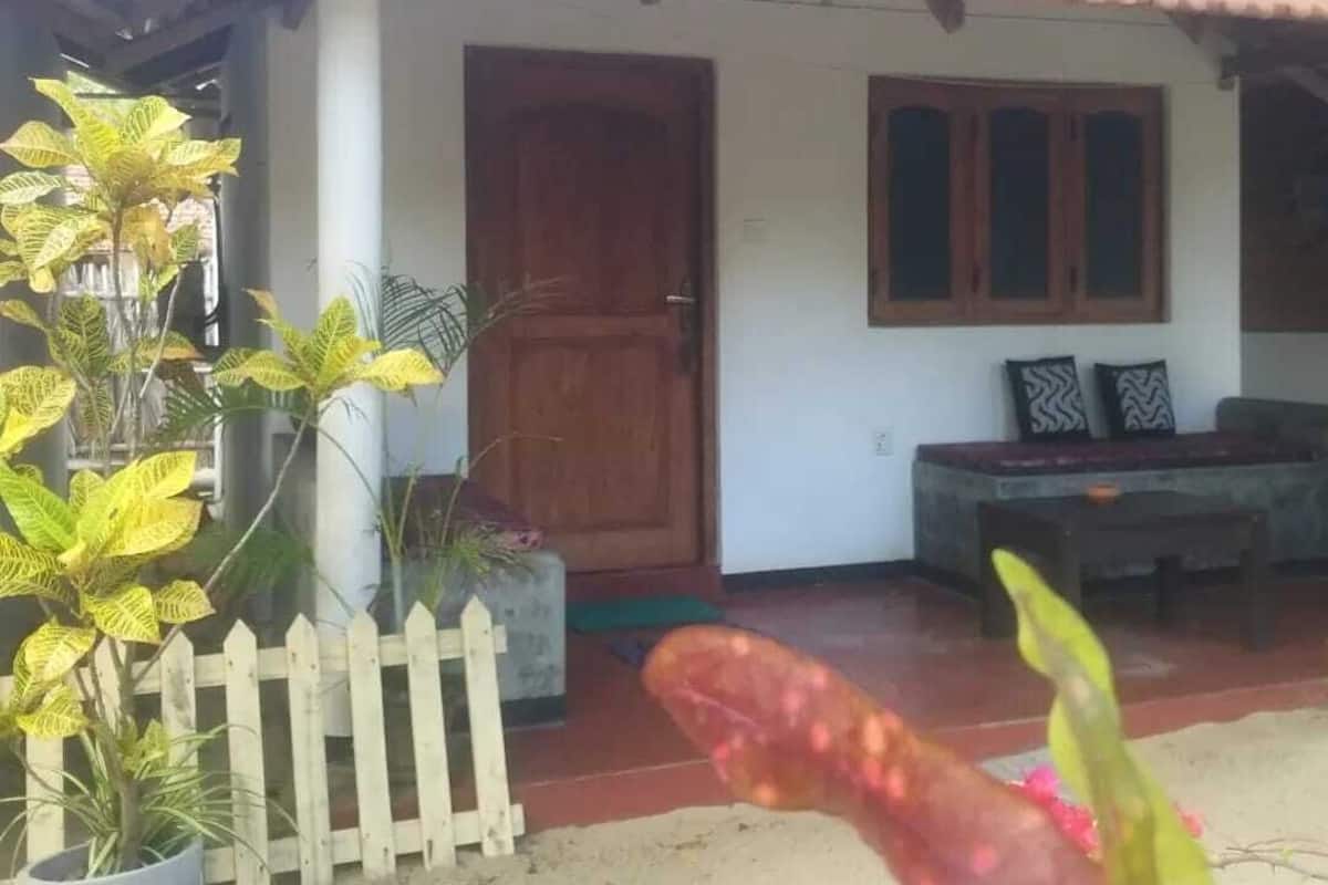 Una casa con techo de tejas, puerta de madera y un banco en el exterior.