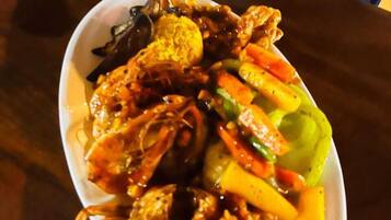 A plate of food with various vegetables and seafood, including crab legs.
