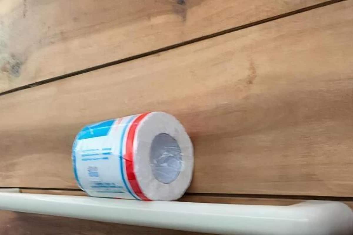 Pared de madera con un estante blanco que sostiene un objeto cilíndrico.