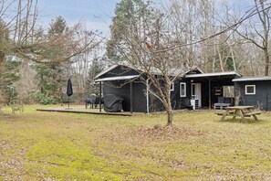 A cabin with a covered patio, a picnic table, and a small garden area.
