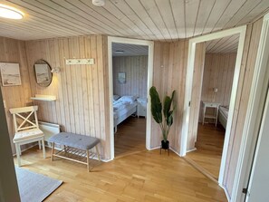 Una stanza con pareti in legno, un letto, una panca e una pianta in vaso.