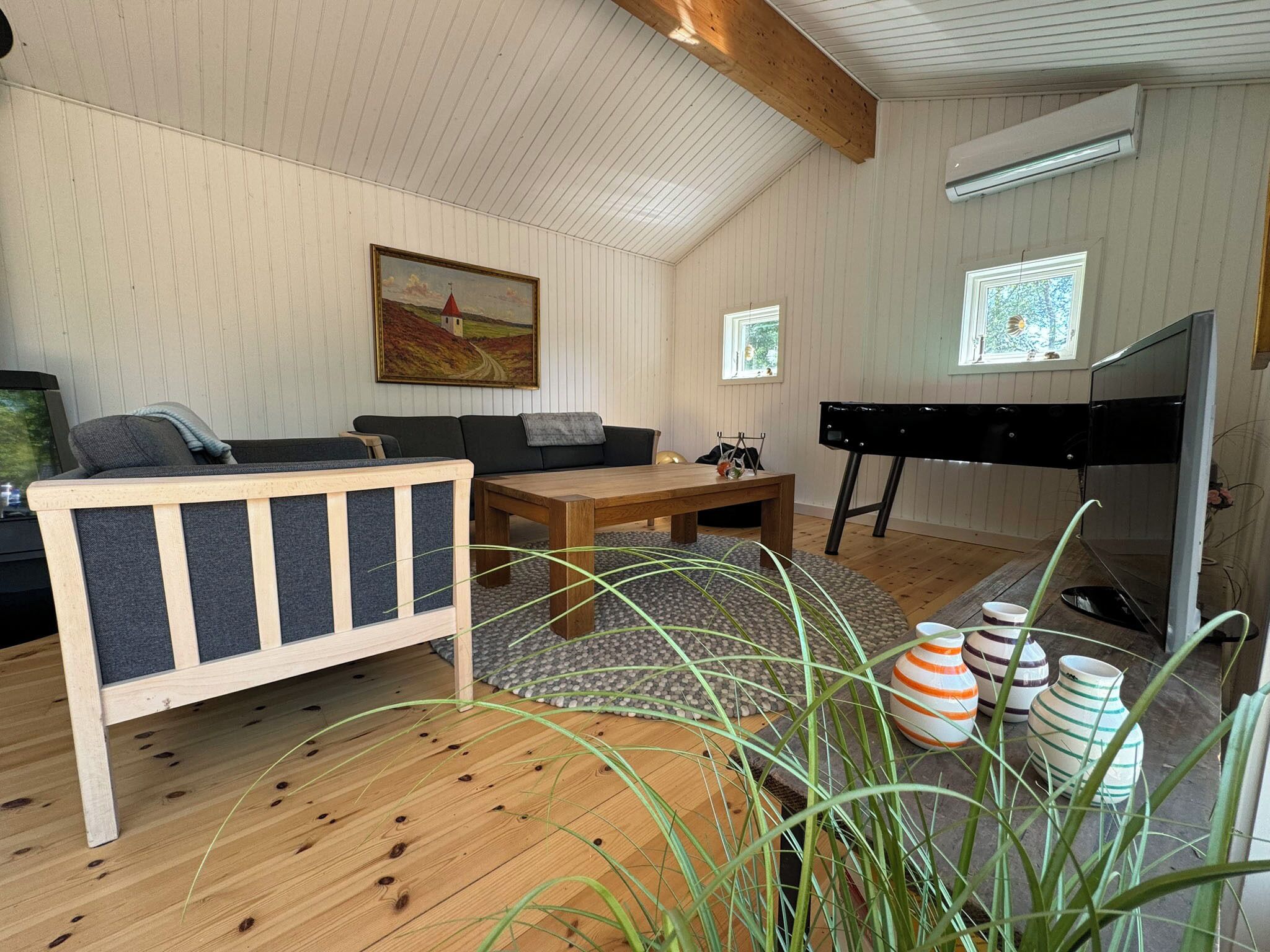 Un salon chaleureux avec un canapé en bois, une table basse et un meuble pour la télévision.
