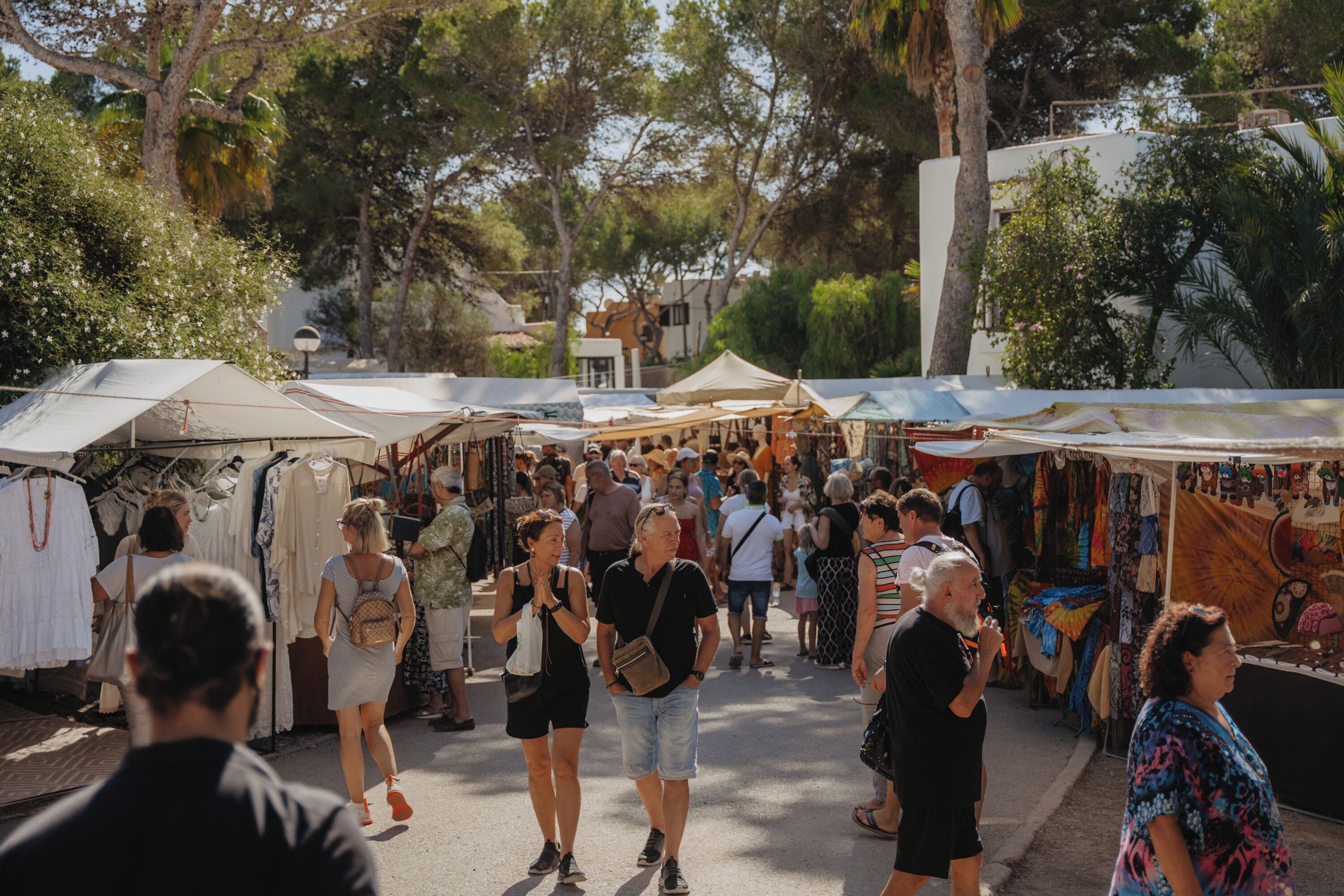 A bustling outdoor market with various stalls and people walking around.
