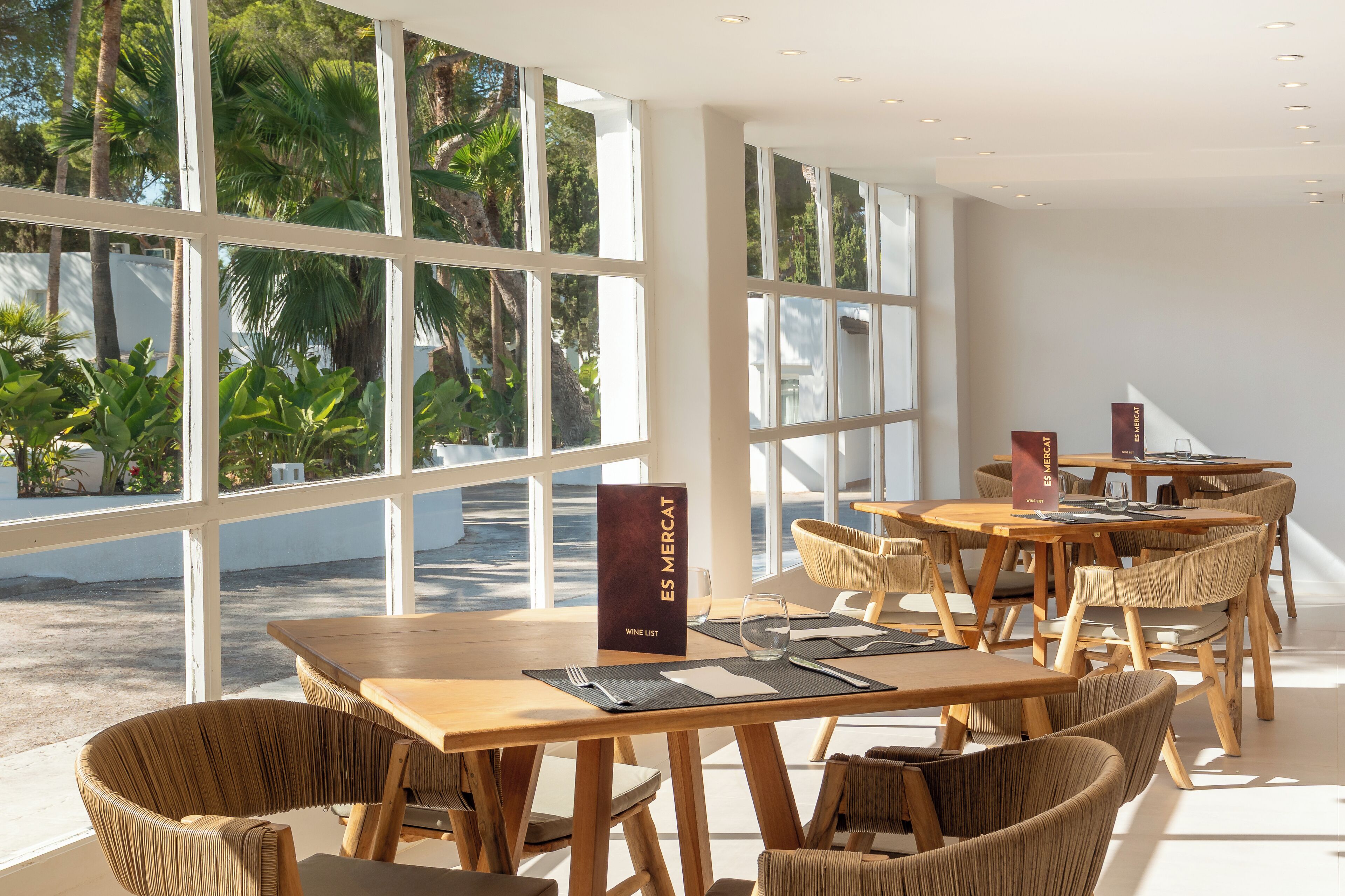 Un restaurant doté de grandes fenêtres, de tables en bois et de chaises en osier.