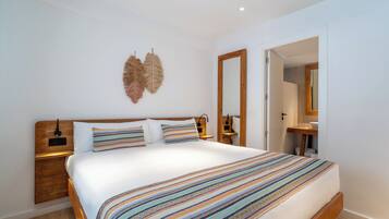 A modern bedroom with a large bed, wooden headboard, bedside tables, and a mirror.