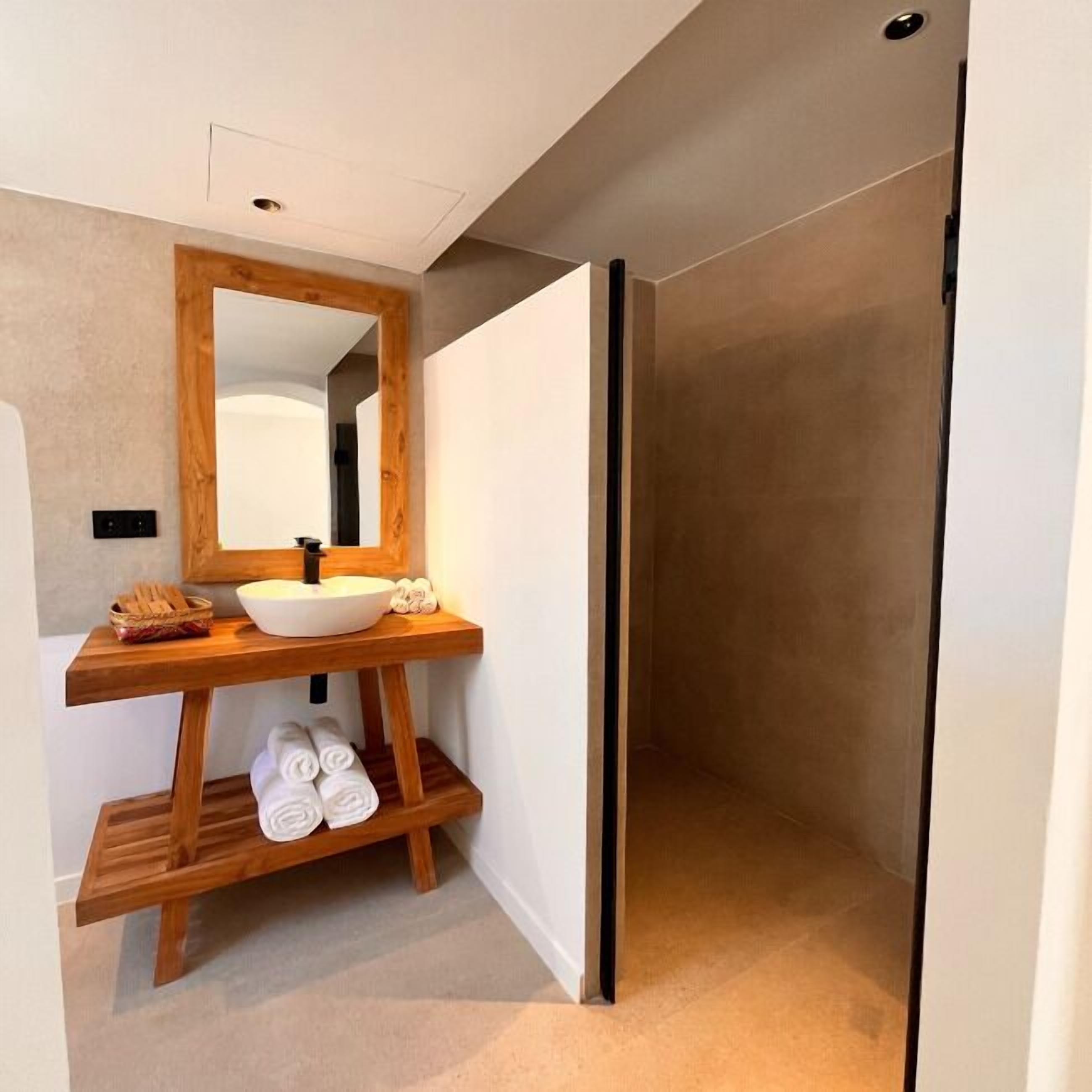 Un baño moderno con tocador de madera, un espejo grande y lavamanos integrado.