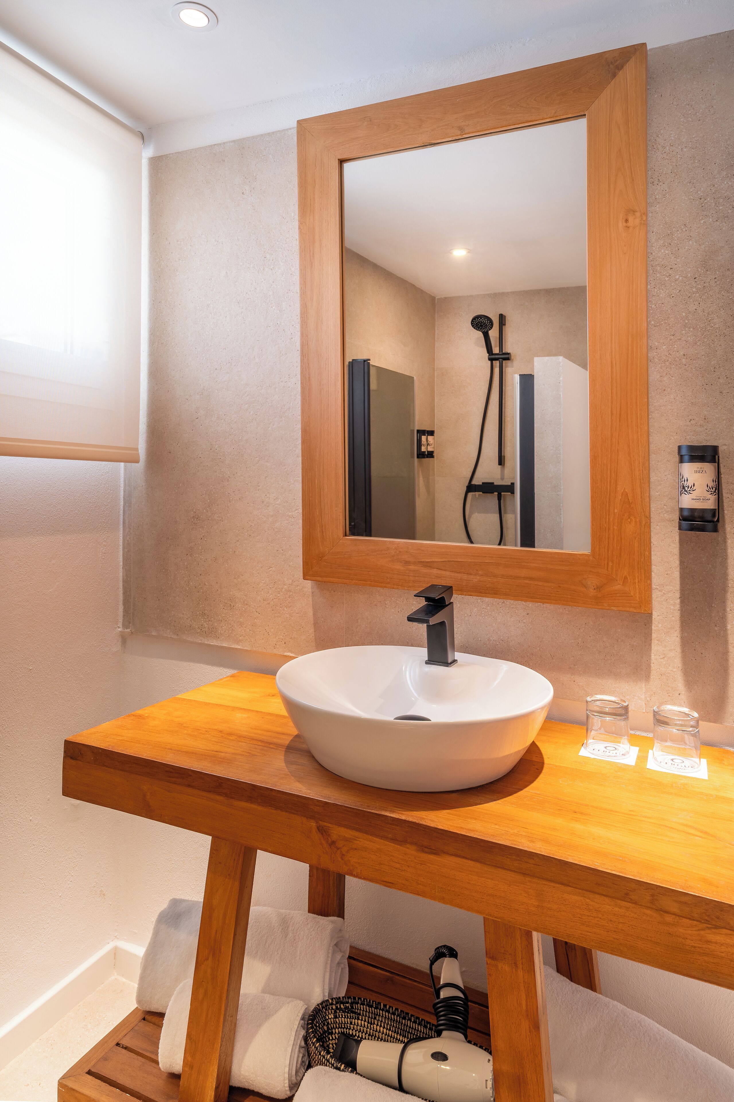 Un baño con tocador de madera, lavamanos blanco y espejo.