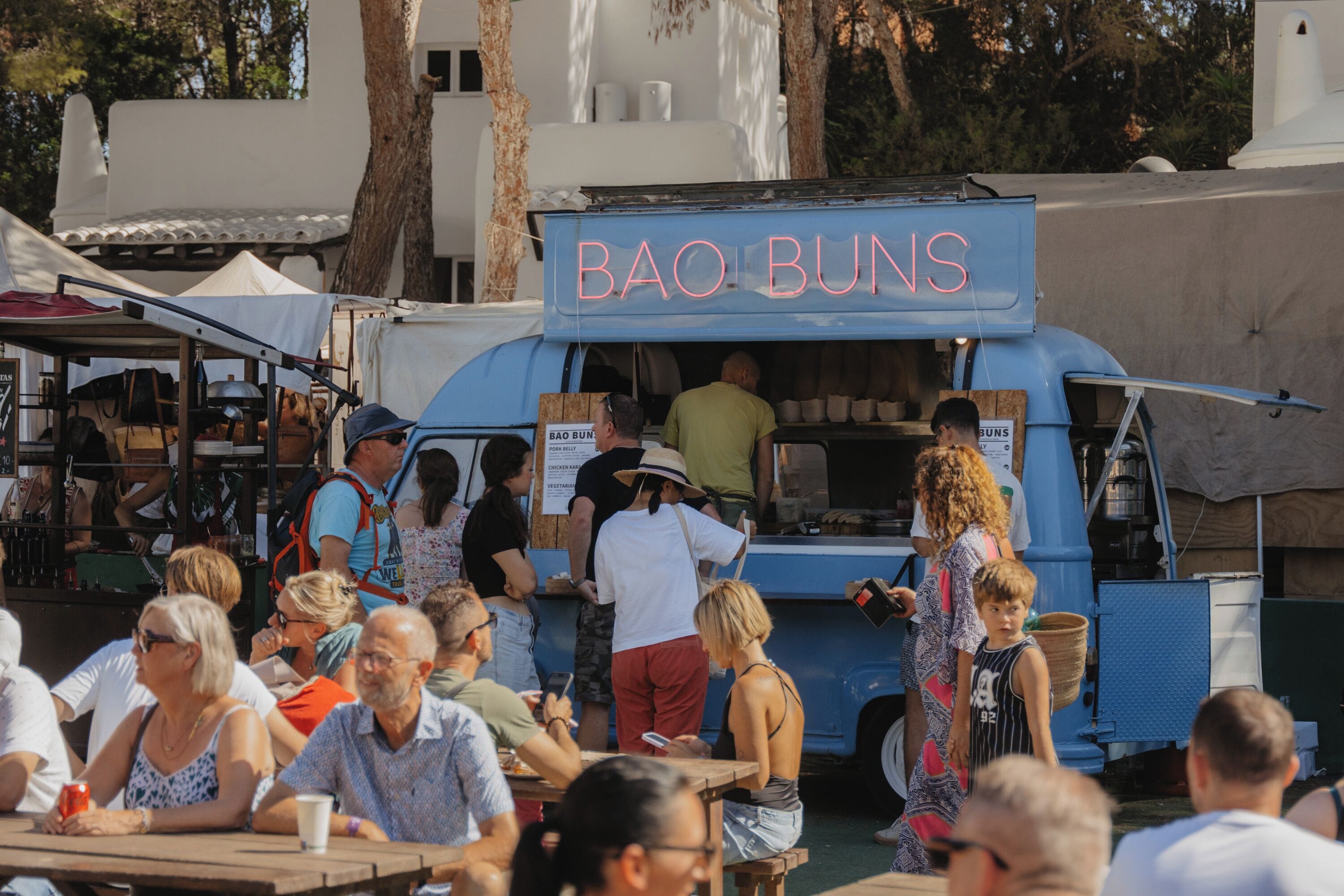 Un camión de comida llamado "BAO BUNS" con exterior azul y letras rosadas.