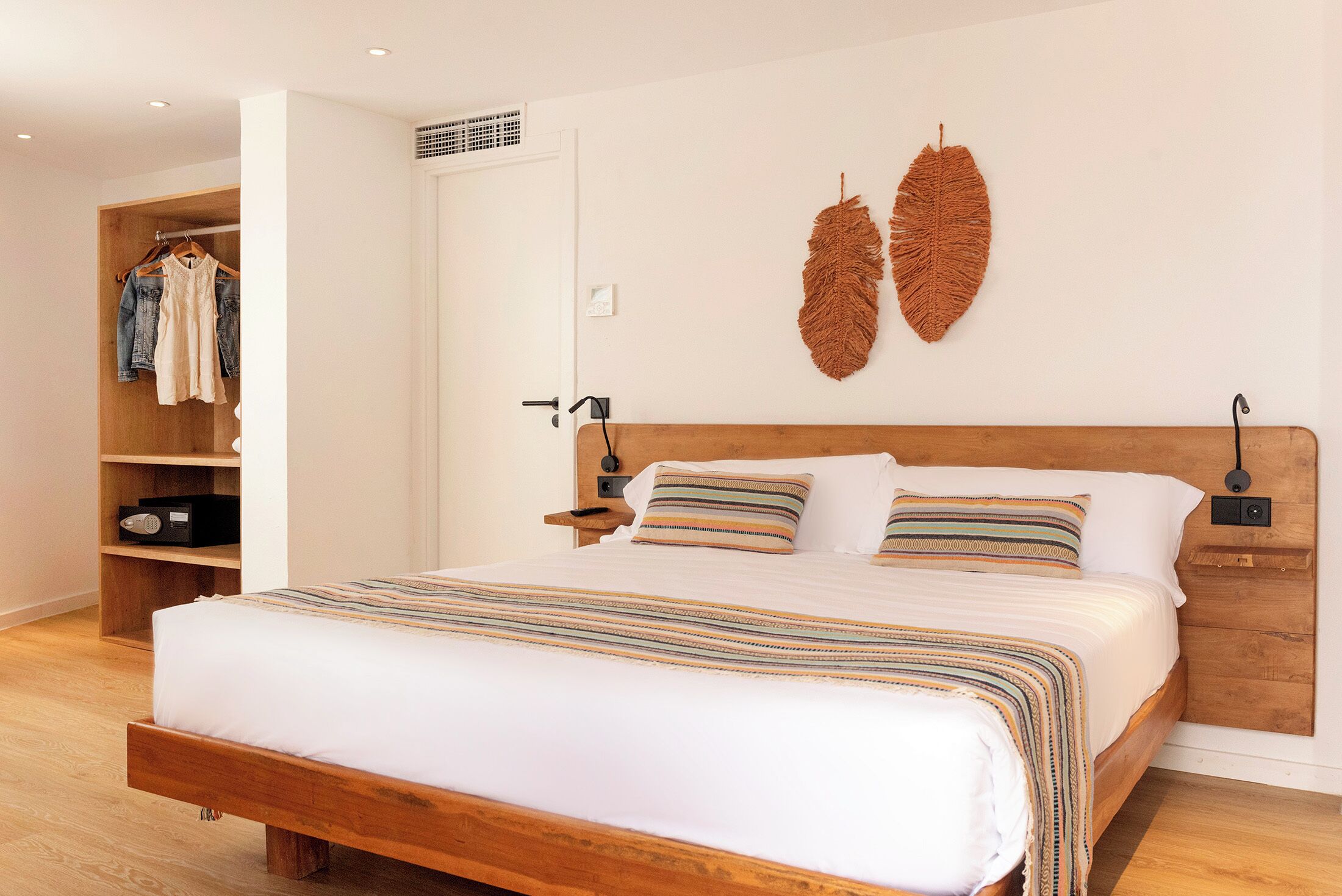 A bedroom with a wooden bed, a wardrobe, and two wall-mounted decorative leaves.
