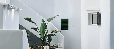 A white building with a staircase, green shutters, and flower planters.