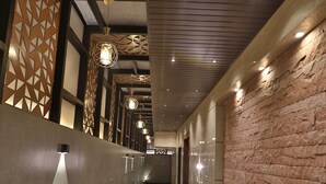 A corridor with patterned walls, a marble floor, and pendant lighting.