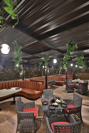 Een restaurant met rieten meubels, zachte zitplaatsen en hangplanten.
