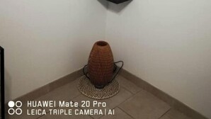 A room with a mounted television, a potted plant, and a decorative vase on the floor. - 1 Bedroom Apartment in Beauvoisin (Beauvoisin)