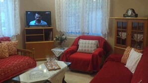 Una sala de estar con un sofá rojo, un televisor y un mueble.