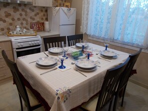 A dining area with a table set for four, including plates, glasses, and cutlery. - ΜΙΚΡΟ ΣΠΙΤΑΚΙ (Κοζάνη)