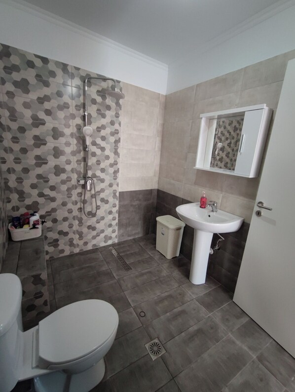 A bathroom with a shower, toilet, sink, and storage cabinet. - ΜΙΚΡΟ ΣΠΙΤΑΚΙ (Κοζάνη)