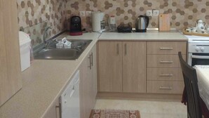 Cocina compacta con armarios de madera, un lavamanos, una cafetera y un hervidor.