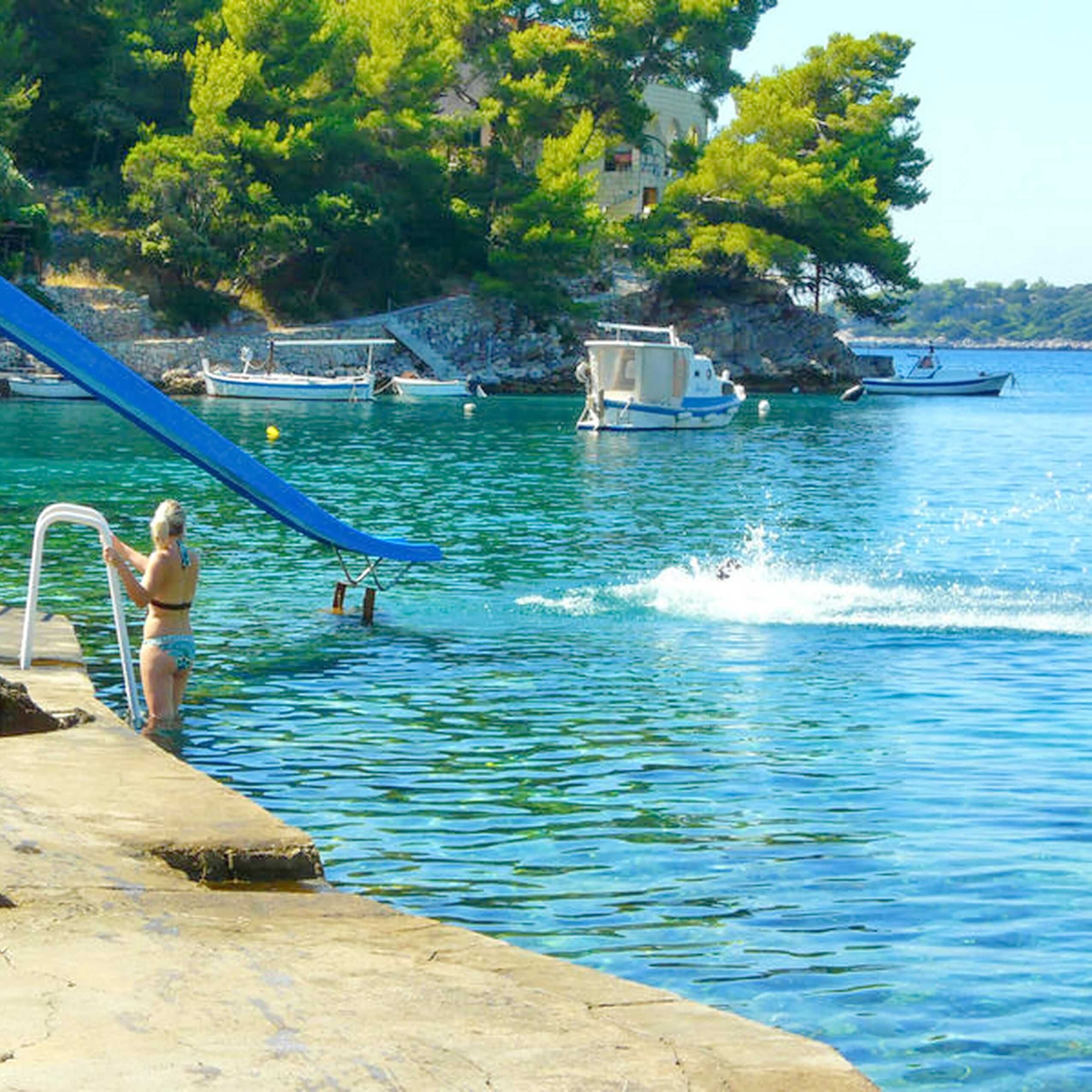 Une rive dégagée avec une rampe de mise à l’eau pour bateaux, une eau calme et des bateaux en arrière-plan.