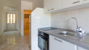 A modern kitchen with white cabinets, a stainless steel sink, and a black oven. - Apartments Katica's Place (Blato)