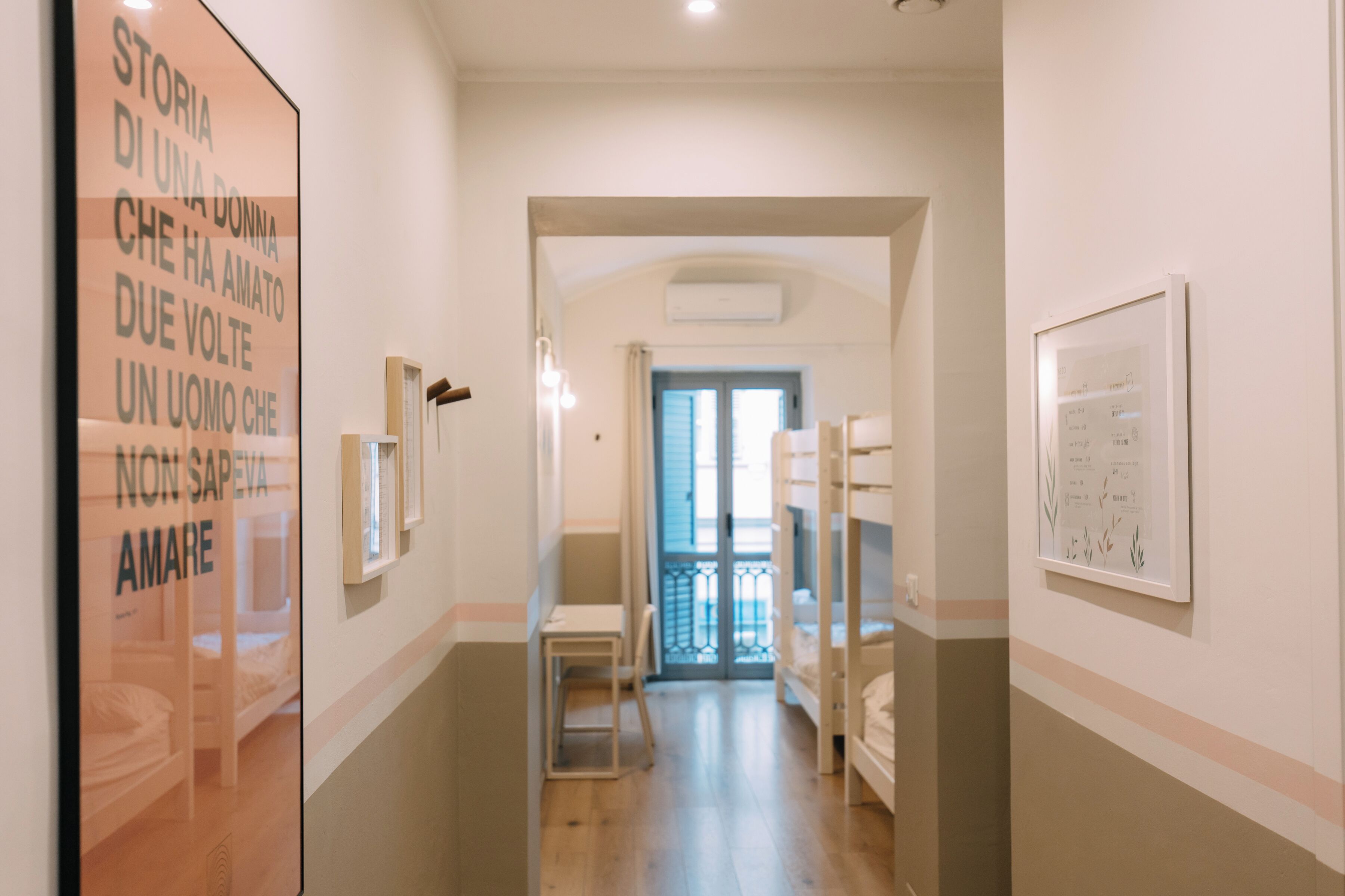 A hallway with bunk beds, a framed picture on the wall, and a poster on the left.