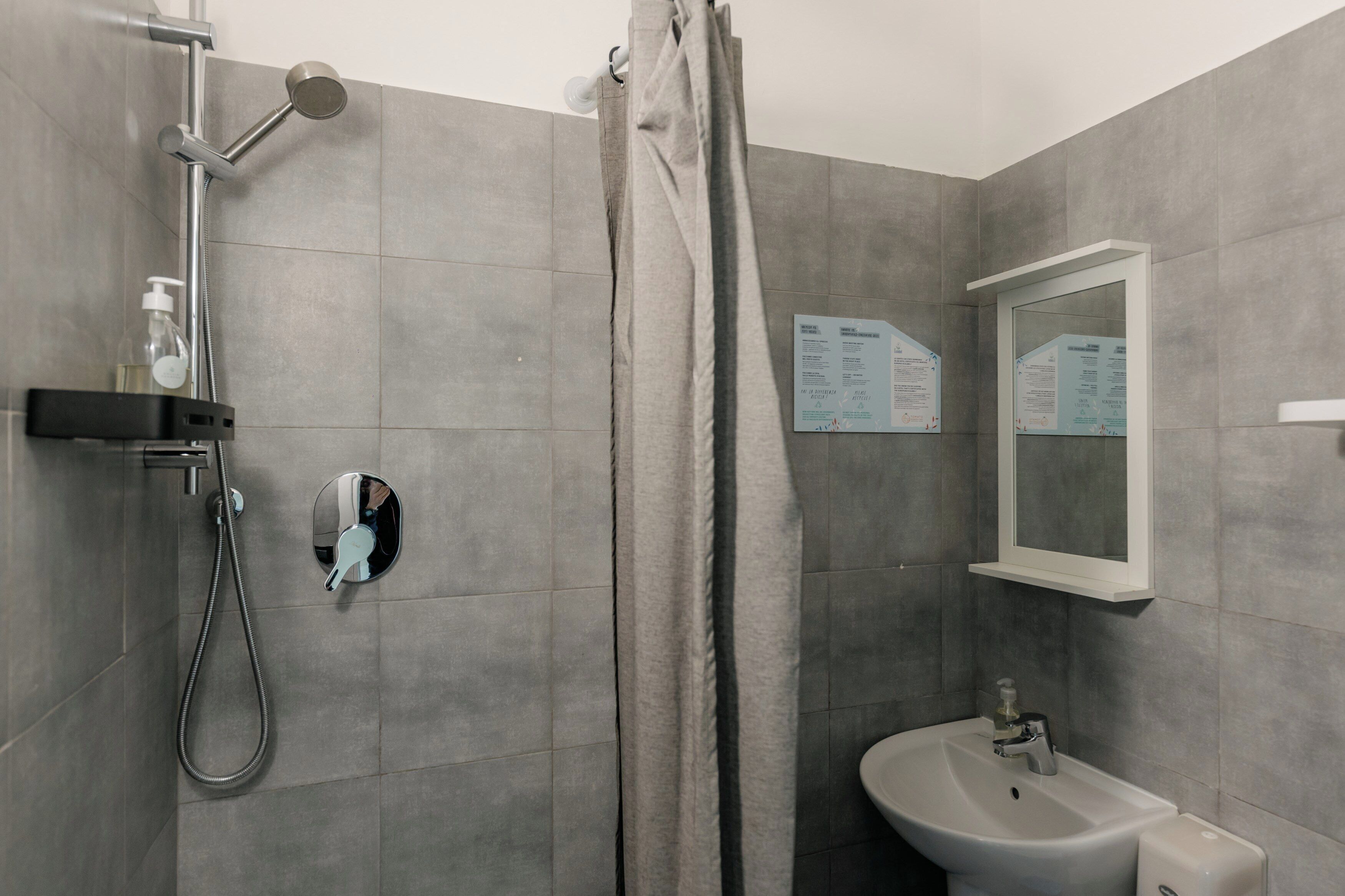 A bathroom with a shower, a sink, and a mirror.