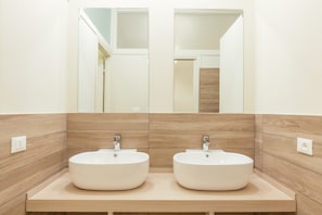 A bathroom with two sinks, wooden paneling, and a mirror above. - Tomato Urban Retreat (Turin)