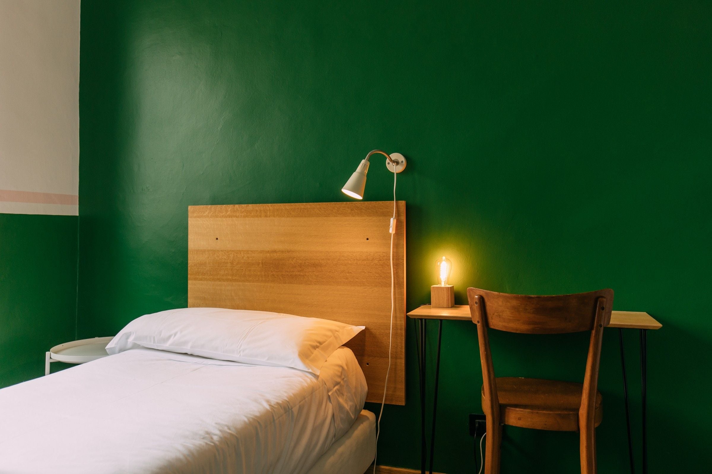 Una habitación con cama, escritorio, silla y lámpara.
