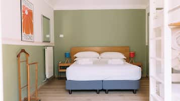 Un dormitorio con cama, mesitas de noche, radiador, suelo de madera e imagen colgada en la pared.