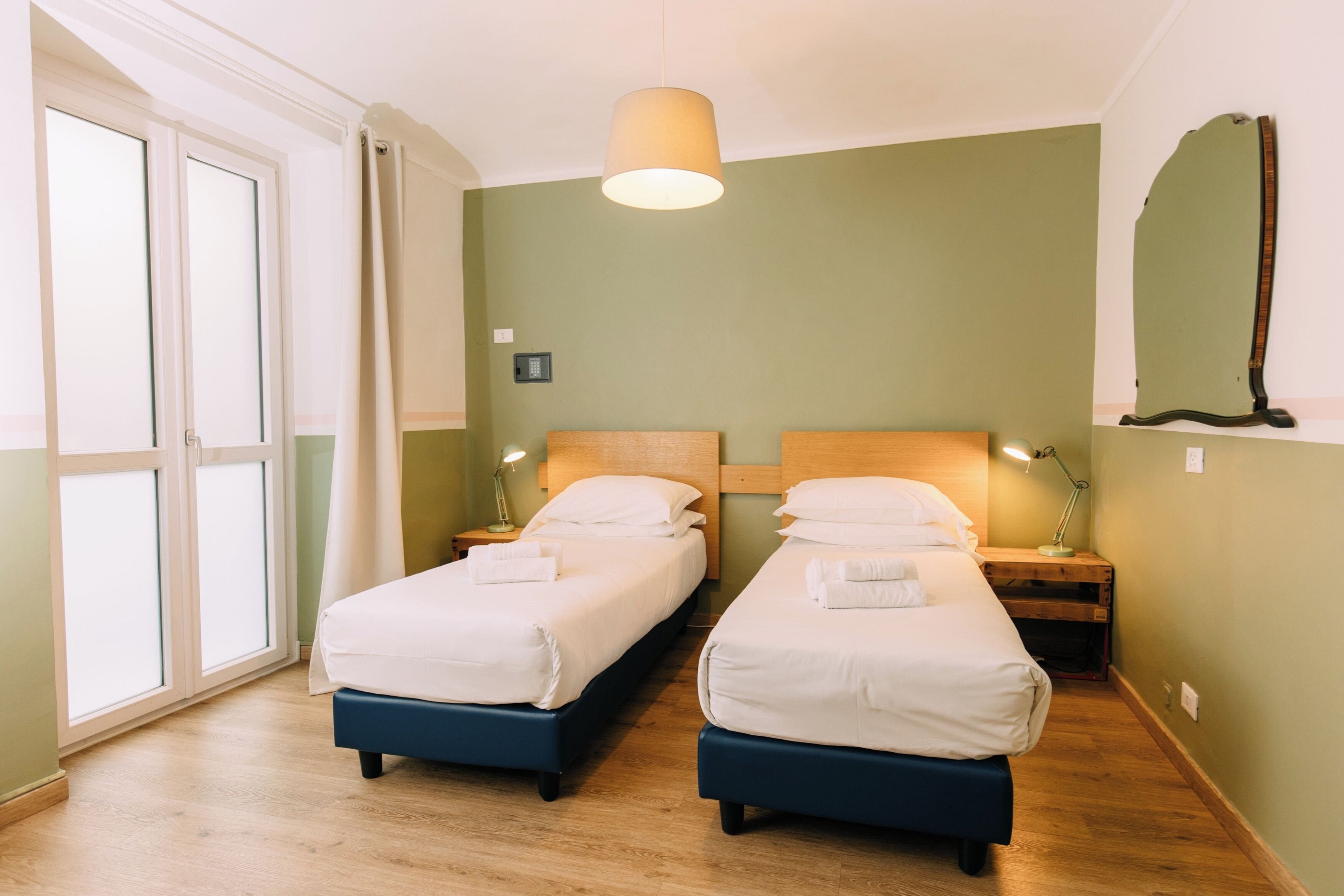 Ett hotellrum med två sängar, ett stort fönster och en taklampa.