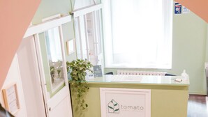 A reception desk with a 'tomato' sign, a plant, and a window with blinds. - Tomato Urban Retreat (Turin)