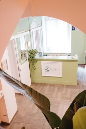A reception desk with a 'tomato' sign, a plant, and a window with blinds. - Tomato Urban Retreat (Turin)