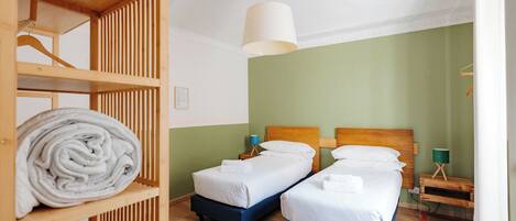 A room with two beds, a wooden wardrobe, and a hanging light fixture.