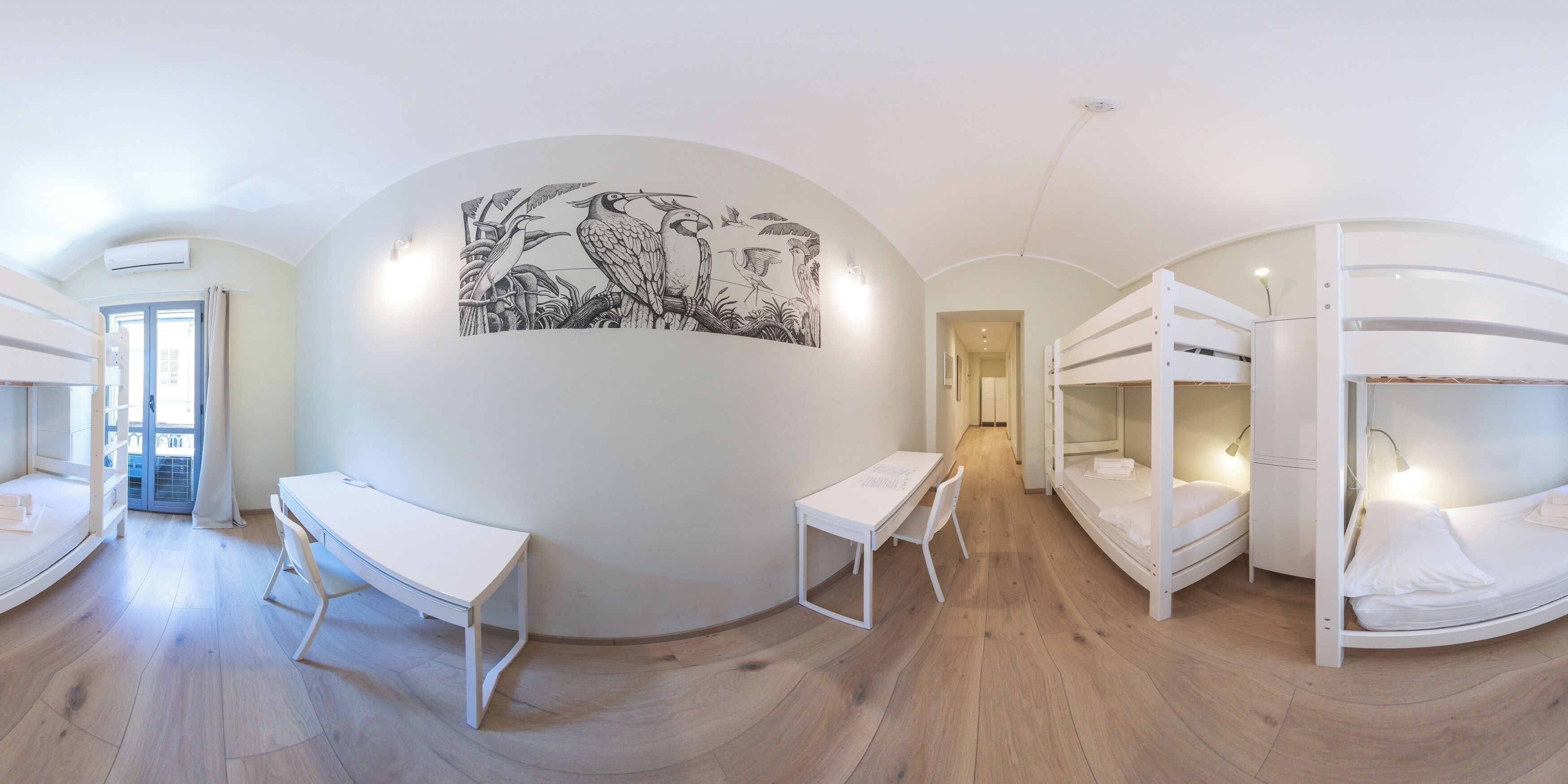 A room with bunk beds, a desk, and a large wall mural.