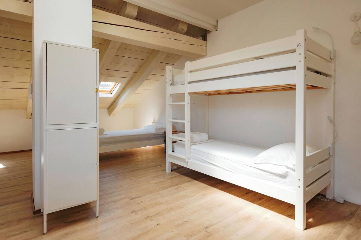 A bunk bed room with a white wardrobe and a skylight.