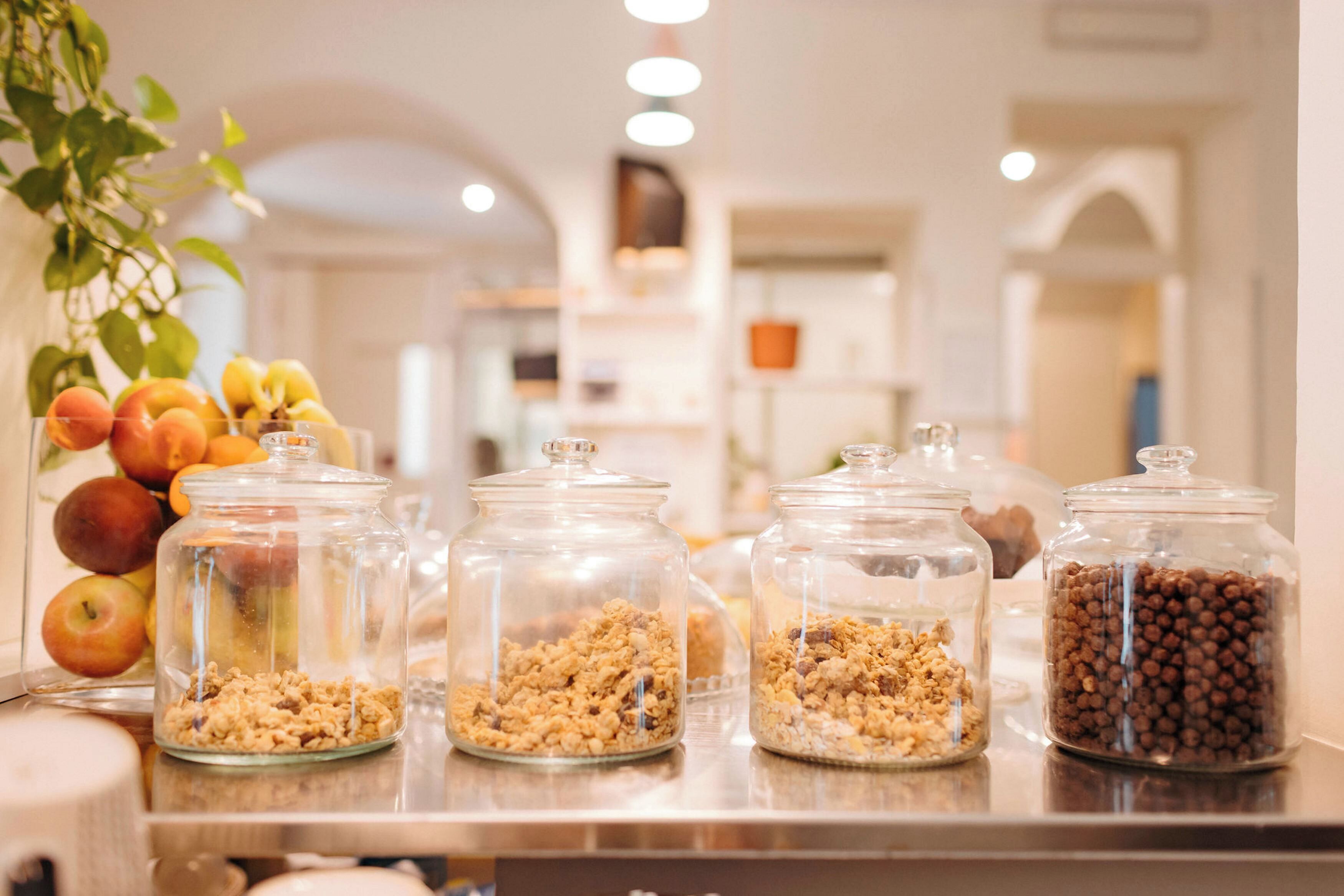 Una barra de desayuno con diversos alimentos en frascos de vidrio, como frutas y granola.