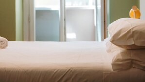 Habitación de hotel con una cama, una lámpara colgante y vistas al exterior.
