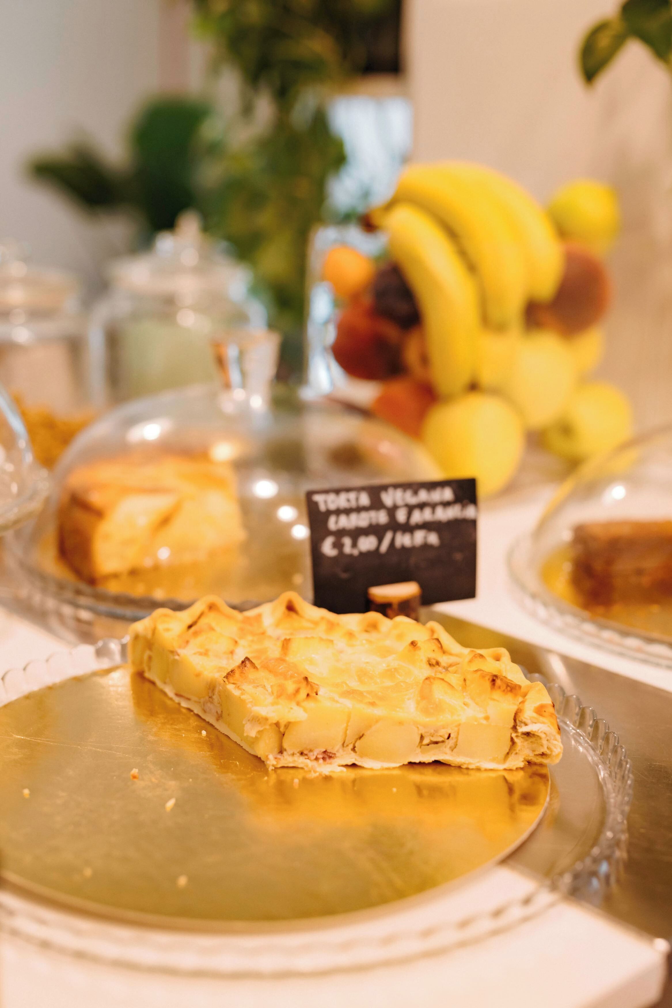 A dessert display with various pastries and a sign indicating a vegan tart priced at 2.00.