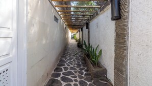 A narrow stone-paved corridor with a bamboo roof structure and potted plants along the walls. - Scallywags Mango (Gili Air)