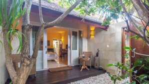 A cozy outdoor area with a wooden deck, a wicker chair, and a dining table. - Scallywags Mango (Gili Air)