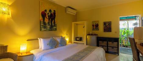 Habitación de hotel con una cama grande, un escritorio, una silla y un balcón con plantas.