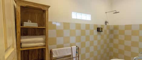 A bathroom with a wooden shelf unit, a white sink, and a checkered tile wall.