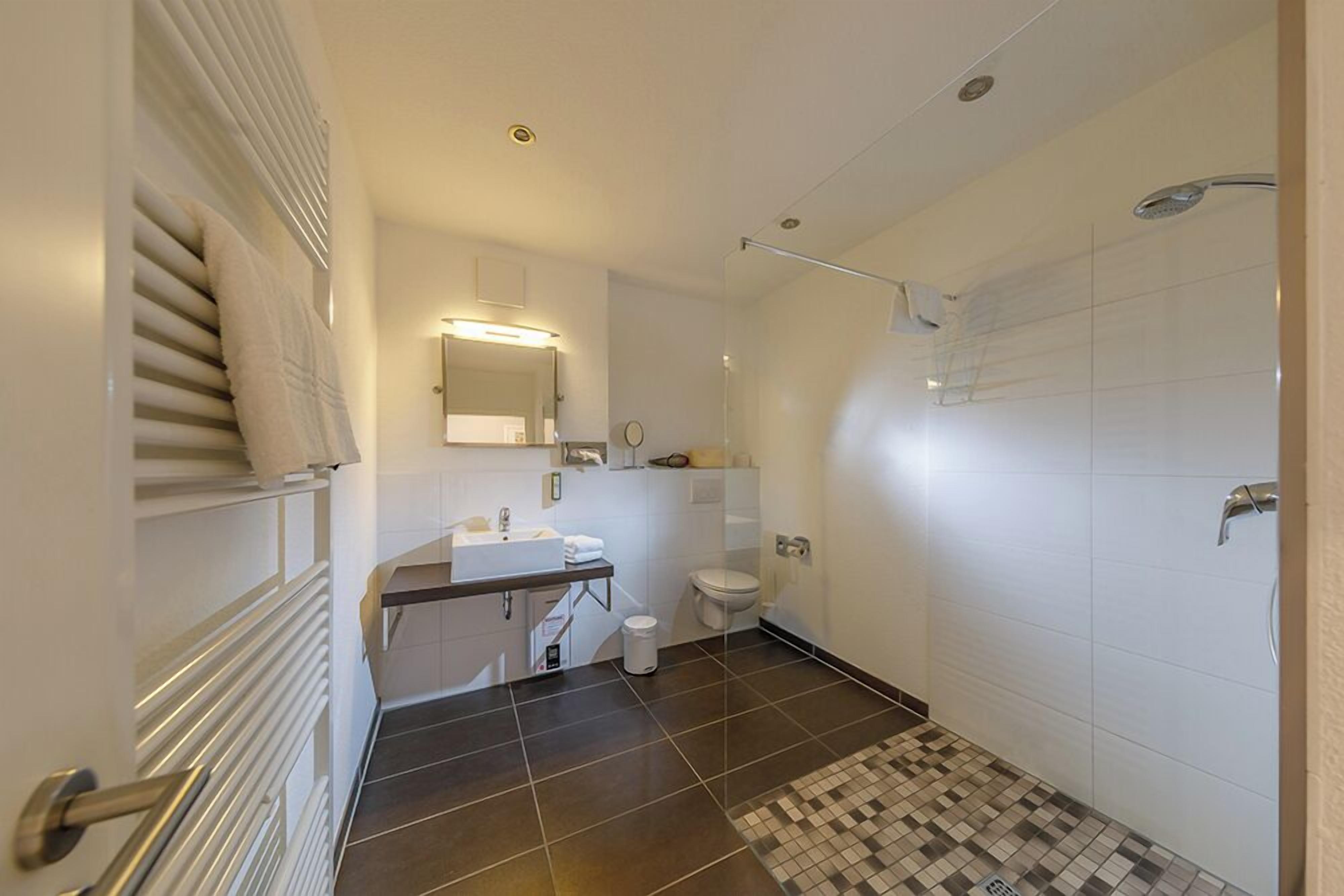 A modern bathroom with a shower, toilet, and sink.