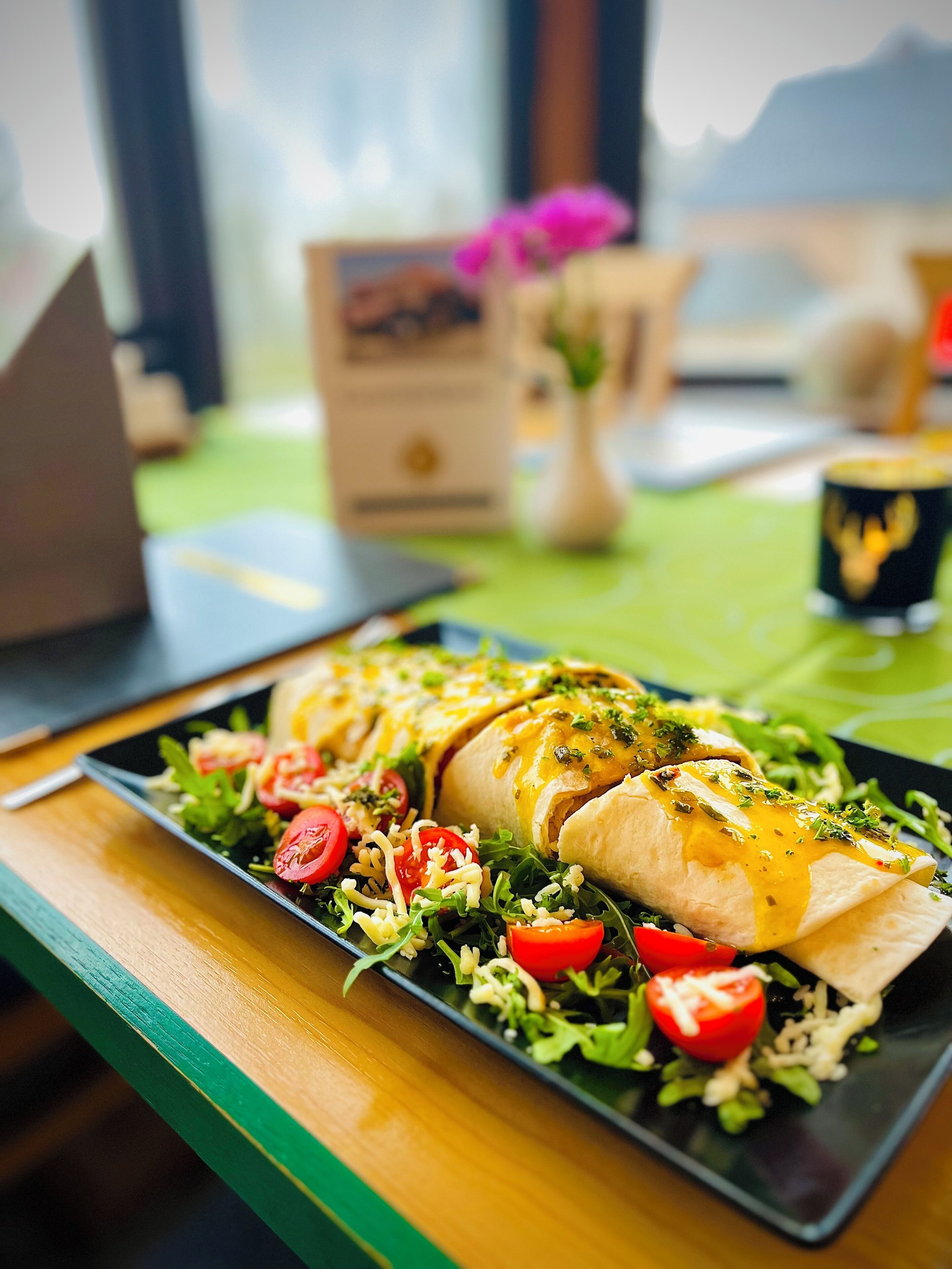 Un repas composé d’un sandwich, d’une salade et d’une boisson, servis sur une table offrant une vue sur les montagnes.
